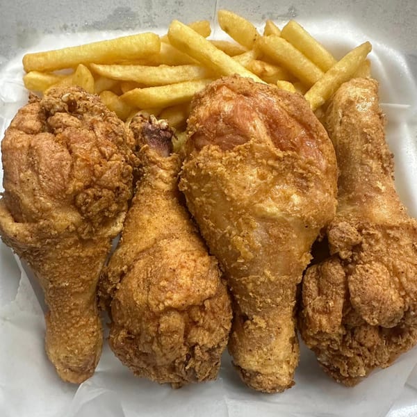 Four pieces of crispy fried chicken and a pile of golden french fries in a white container.
