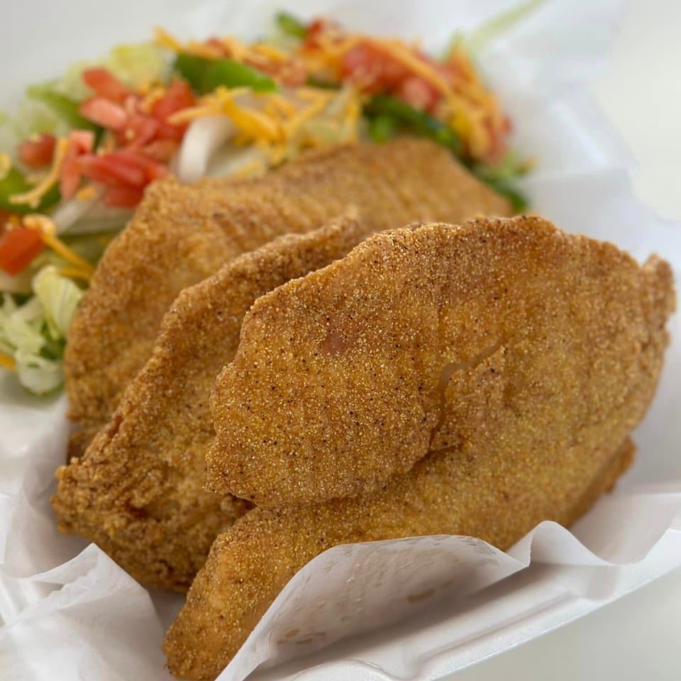 Three crispy fried chicken tenders with a side salad of lettuce, tomatoes, and shredded cheese.